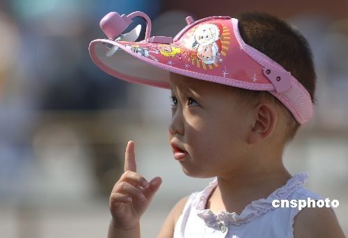 6月24日，北京市最高气温达到37℃，一名孩童头顶带风扇的遮阳帽在街头玩耍。