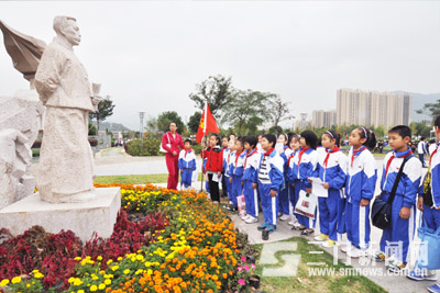 县第四小学学生在革命烈士包定雕像前，倾听老师讲解其事迹