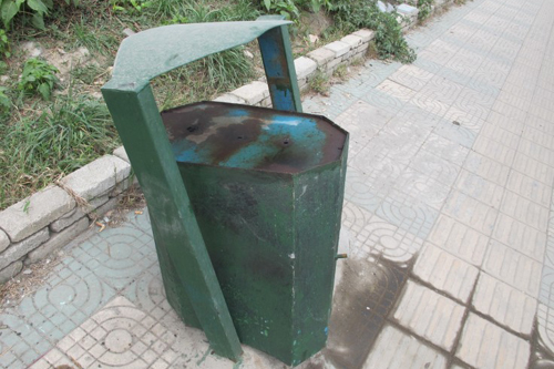 图为黔春路损坏的垃圾桶桶口扣在地上