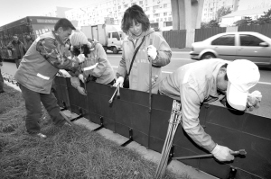 皇姑区崇山东路，工作人员在道路绿化带旁安装防雪盐围挡