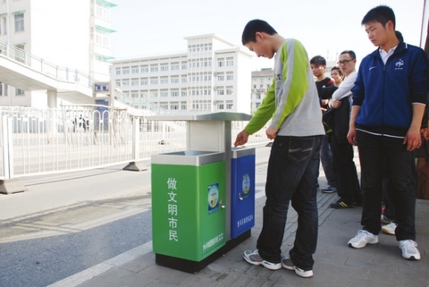 市民正在往分类垃圾箱里扔垃圾。