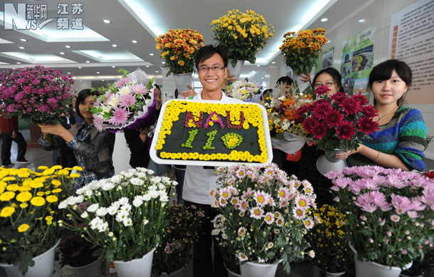 一名学生在展示用菊花摆放成庆祝南农大110周年校庆的图案