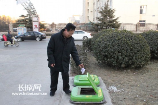 家住附近小区的赵立明老人正在地埋式垃圾箱前投掷垃圾。