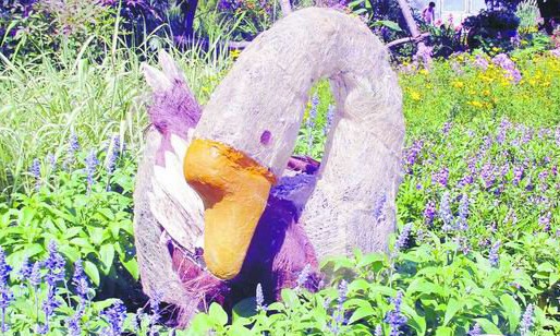 花丛中，用椰棕、树皮、枯叶等废弃材料拼组而成大白鹅给绿地增添些许情趣。