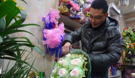 市区某花店业主正在捆扎客人订购的圣诞鲜花。这束由11枝玫瑰组成的鲜花，最终以660元的价格售出。