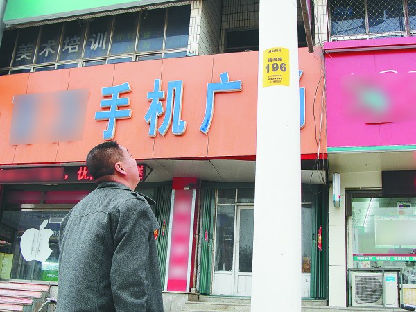 看到路灯杆上多了一个黄色的号码牌，福山区的一位市民正好奇地抬头看。