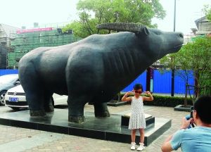 7月20日，一位市民在观赏巨型“中国金融牛”雕塑。