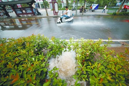 一名骑摩托车的男子将两腿高高跷起涉水通过