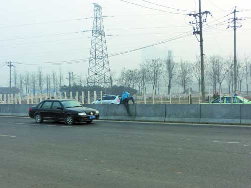西环快速路中间隔离护栏挡板被掰掉许多，一些行人不顾危险从缺口处翻越