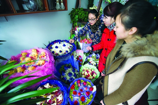 安徽省合肥市文博苑社区的一家花店内，花店老板（左）为前来买花的顾客介绍花的品种。