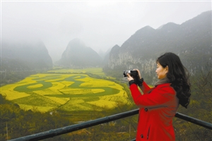 一名游客在拍摄油菜花海中的繁体“龙”字