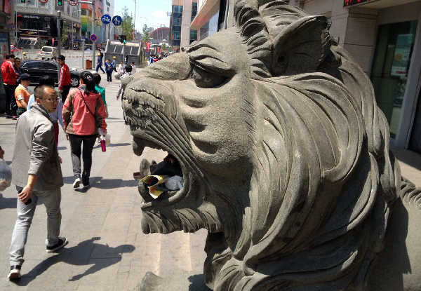 中华路上，一路人从石狮前面走过。