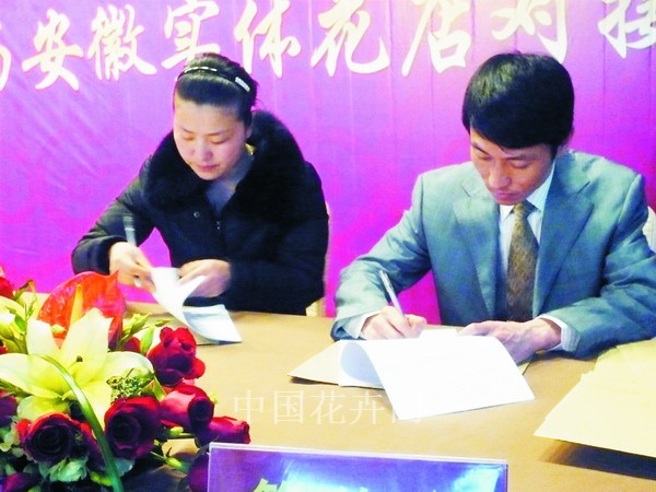公司董事长夏传荣(右)正在与加盟连锁店代表签约